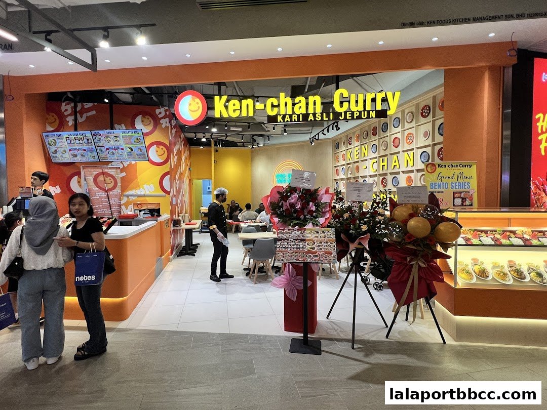 The entrance of Ken-chan Curry, a Japanese curry restaurant, with a vibrant orange facade and menu displays.