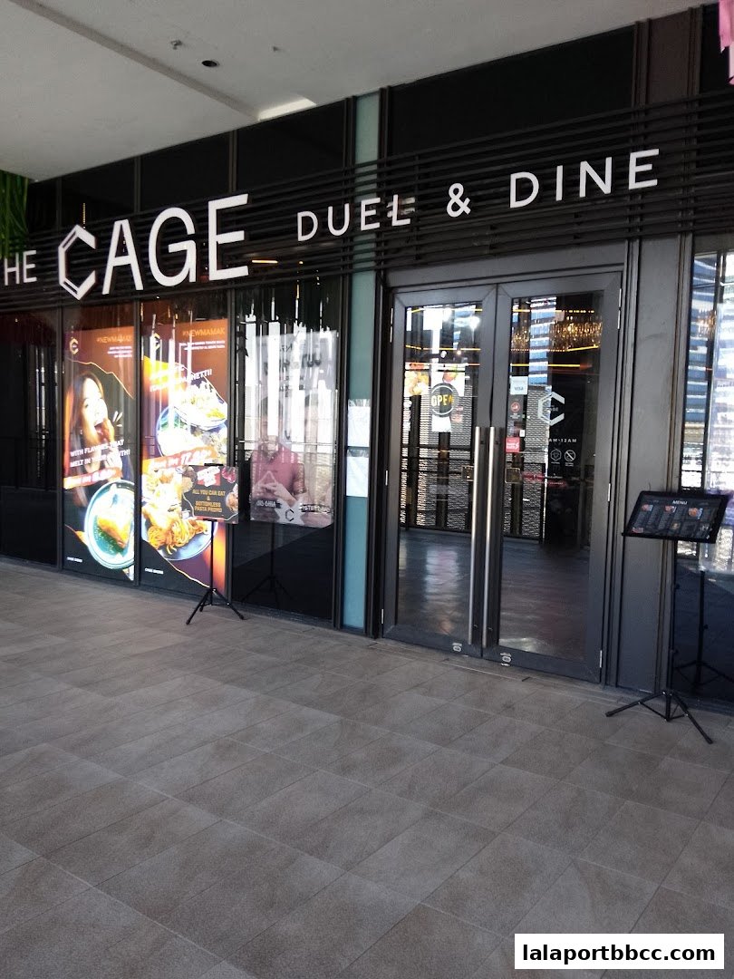 The exterior of 'The CAGE - Duel & Dine' restaurant with its prominent signage and glass doors.