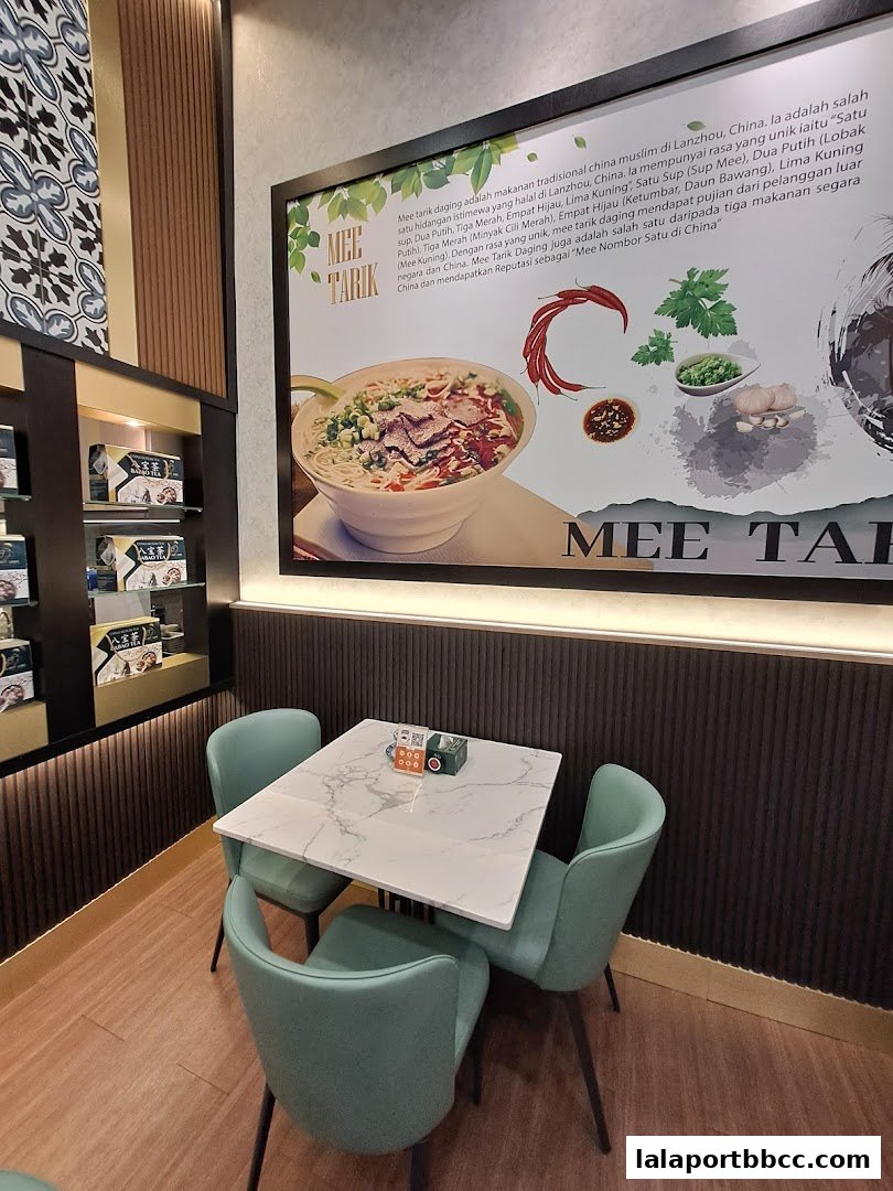 A dining area with a table and chairs, featuring a large poster about Mee Tarik.