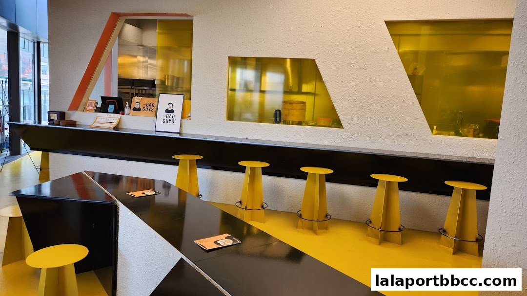 Interior of The Bao Guys restaurant with yellow stools and a modern counter.