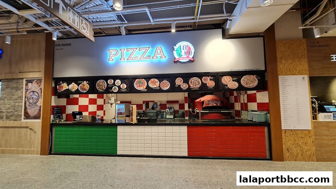 A pizza shop with a neon sign, display of pizzas, and a wood-fired oven.