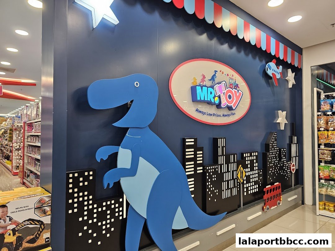 A colorful toy store interior featuring a large blue dinosaur and city skyline decor.