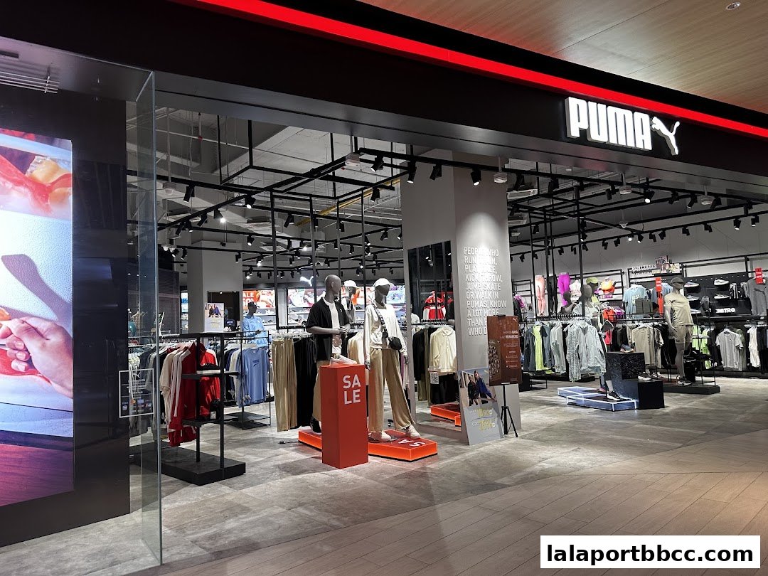 The entrance of a PUMA store showcasing apparel on mannequins and racks, with a prominent "SALE" sign.