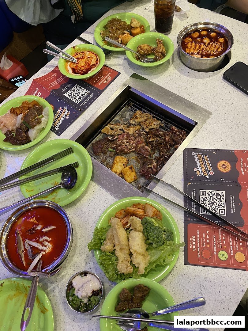 A table laden with various Korean dishes, including grilled meats, fried items, and dipping sauces.