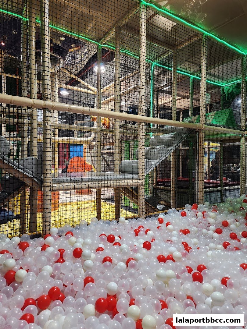 A large indoor playground with a ball pit filled with red and white balls.