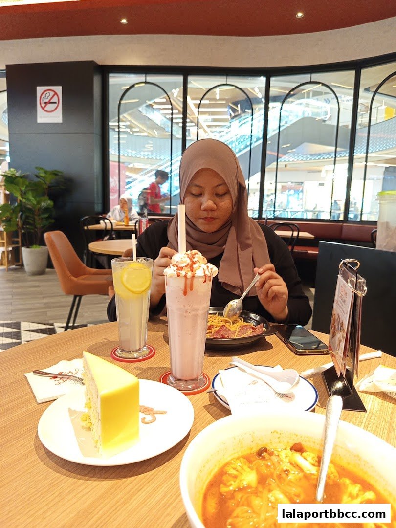 A woman enjoys a meal with cake, milkshake, and soup at Secret Recipe.