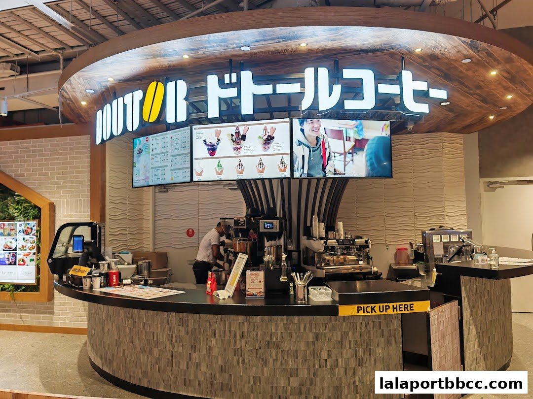 The interior of a Doutor Coffee shop with a counter, espresso machines, and digital menus.