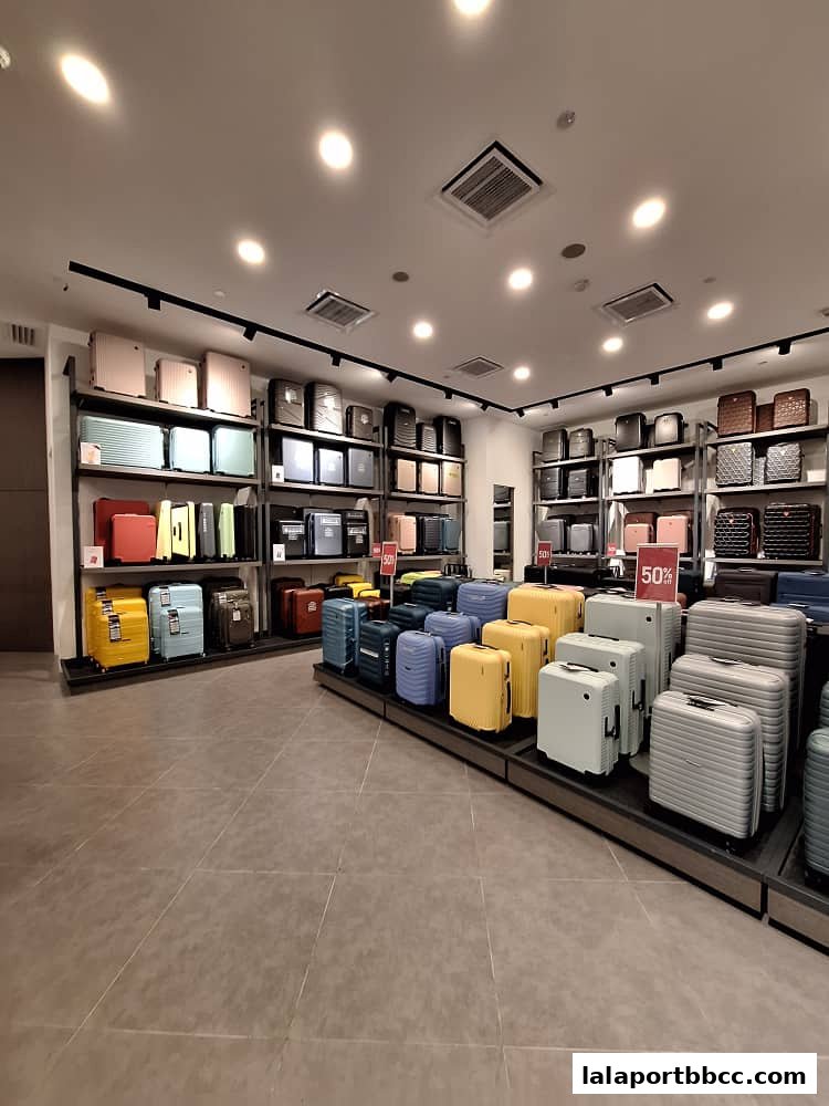 A wide selection of colorful luggage displayed on shelves and stands inside a retail store.