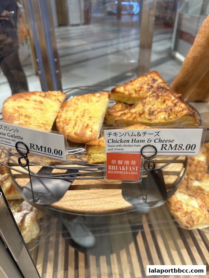 A display of freshly baked bread items, including cheese galette and chicken ham and cheese toast.