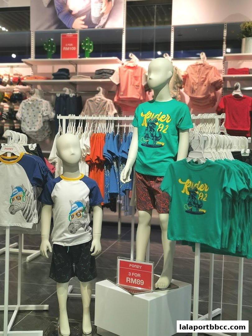 Mannequins display colorful children's clothing, including t-shirts and shorts, with promotional signage.