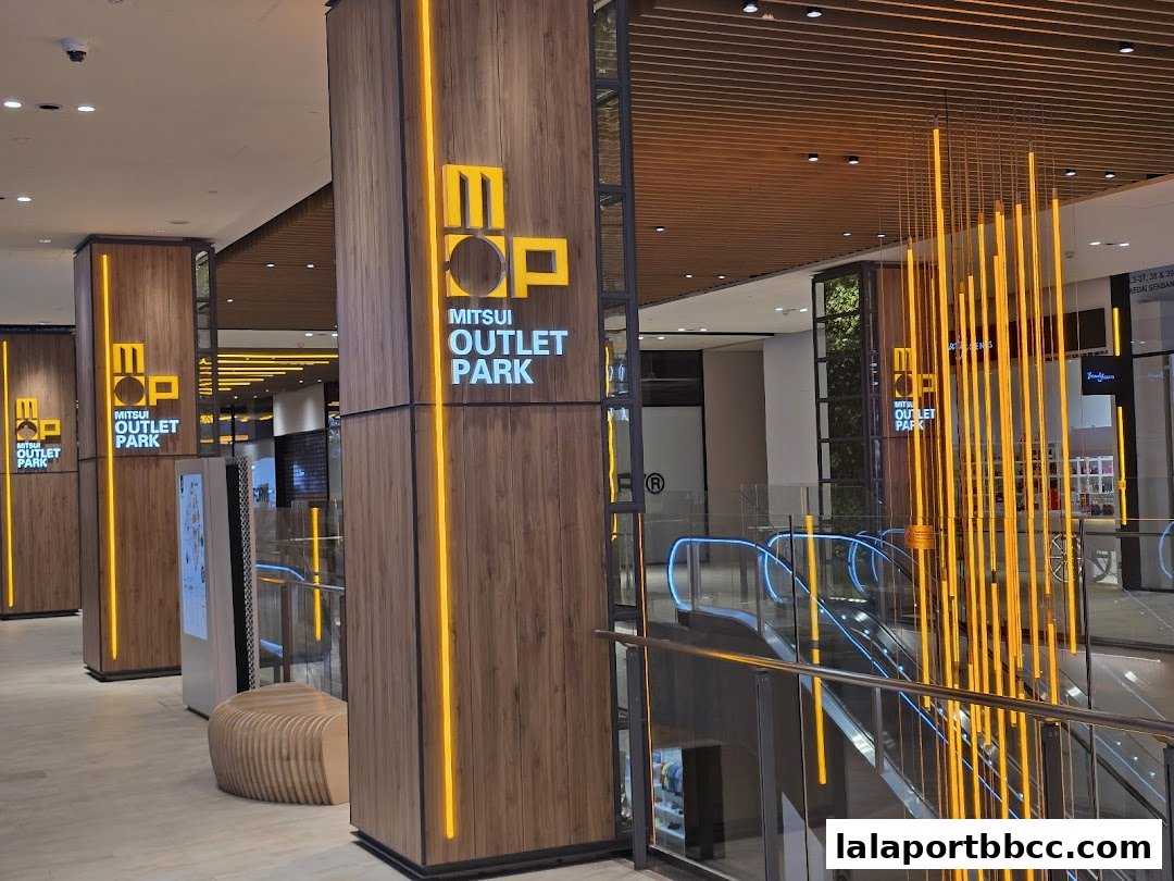 Modern interior of a shopping mall with illuminated pillars and escalators.