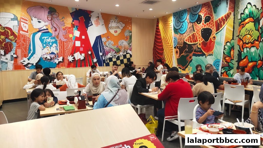 Diners enjoy meals in a restaurant with vibrant, Japanese-inspired murals on the walls.