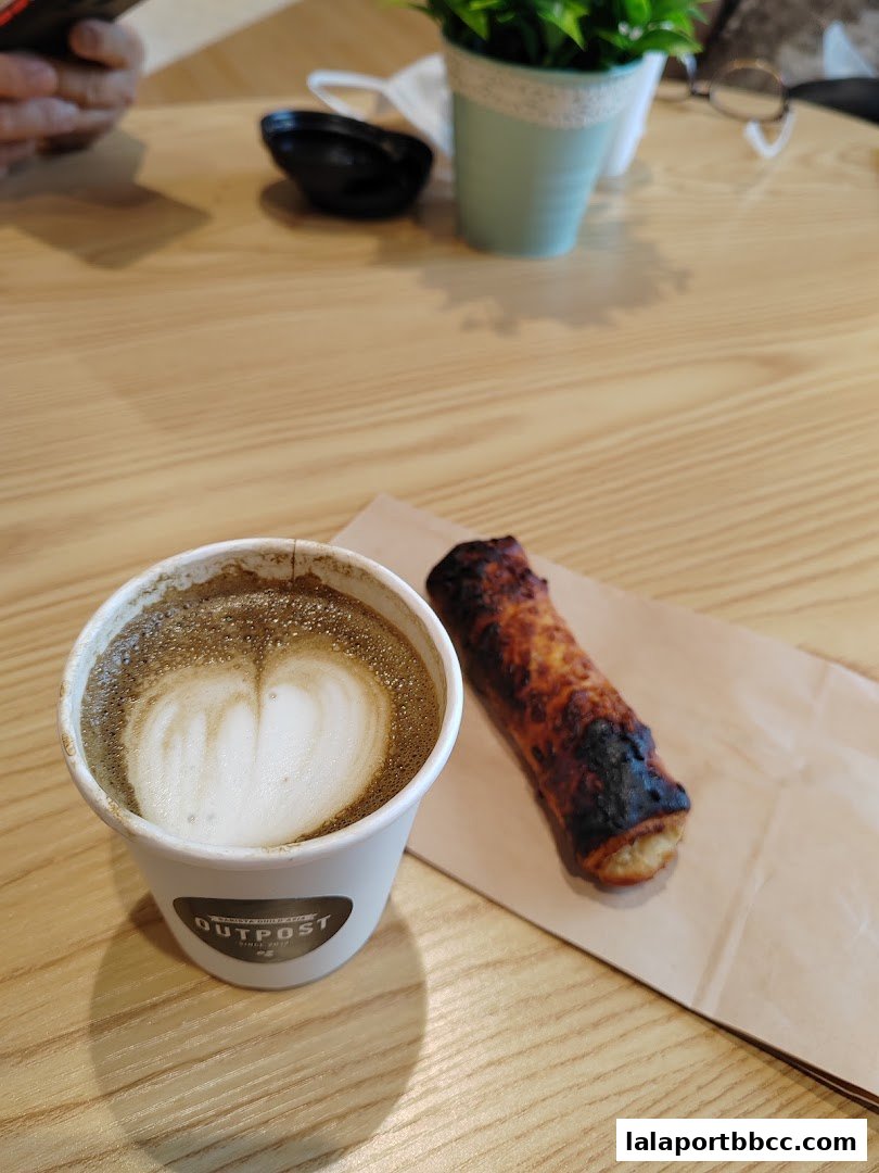 A cup of coffee with latte art and a pastry on a wooden table.