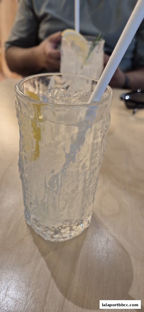 A close-up of a refreshing drink with ice and a lemon slice, served in a textured glass.