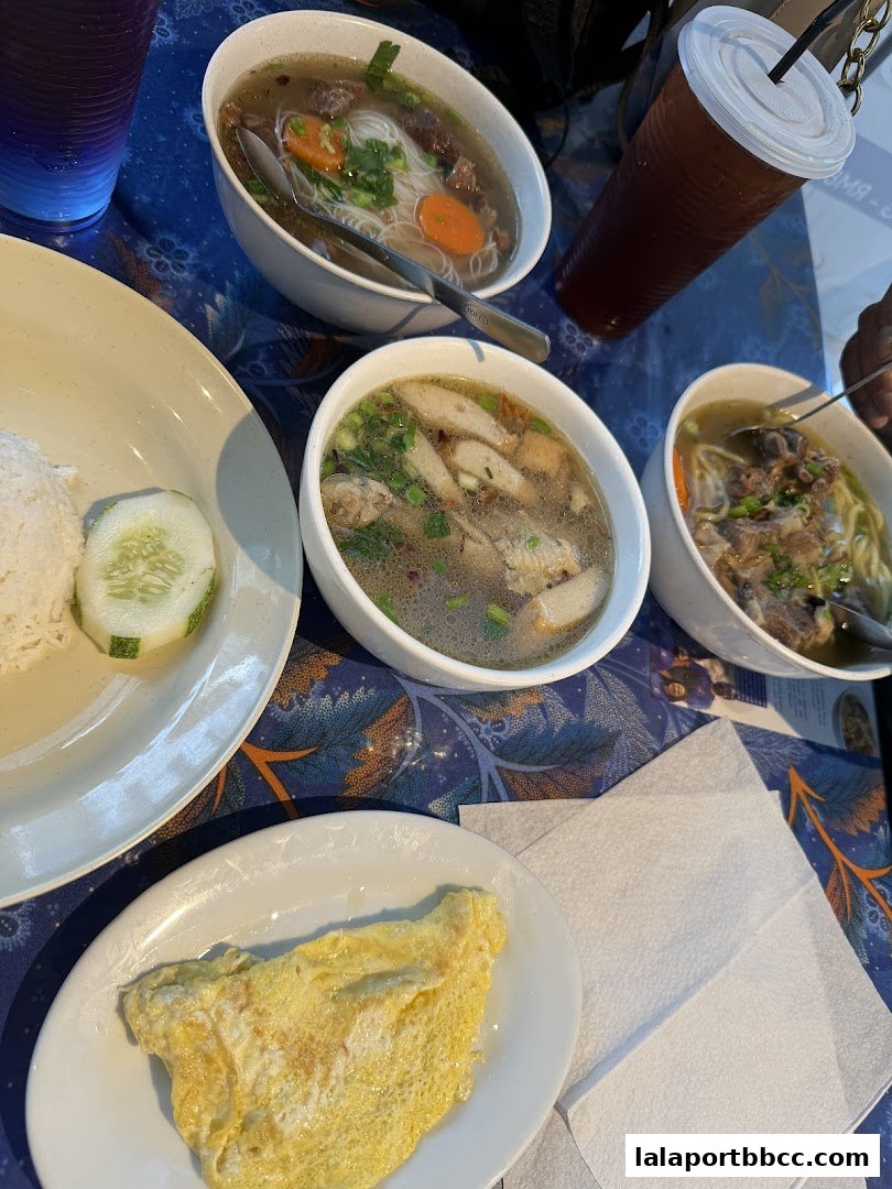 A table setting with three bowls of soup, rice, an omelet, and a drink.