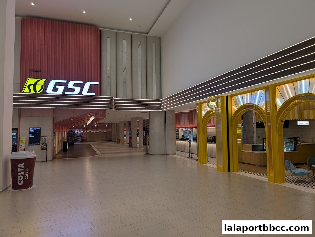 Interior view of a shopping mall with a GSC cinema entrance and a brightly lit food stall.