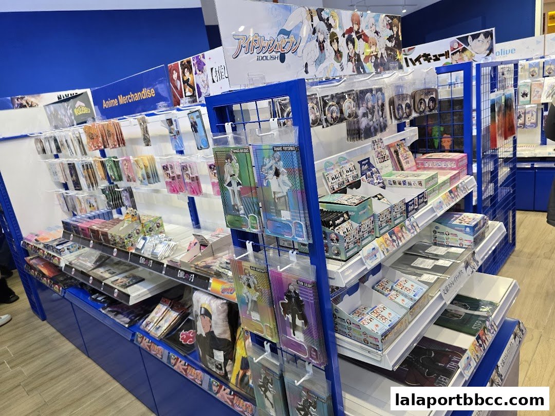 A brightly lit store aisle filled with anime merchandise, including posters, keychains, and boxes.