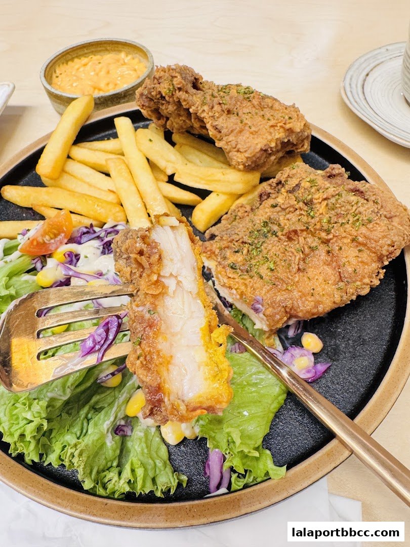 A plate of crispy fried chicken with fries, salad, and dipping sauce.