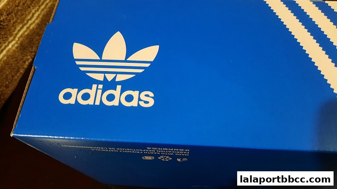A blue Adidas Originals shoebox with the iconic trefoil logo and three stripes.
