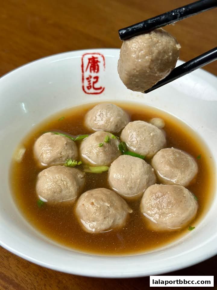A bowl of Hong Kong-style meatballs in broth, with chopsticks picking one up.