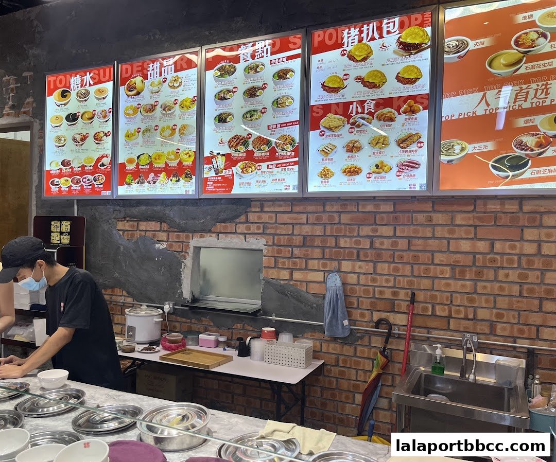 A brightly lit menu board displaying various desserts and snacks at Lol Soon Kee Desserts.