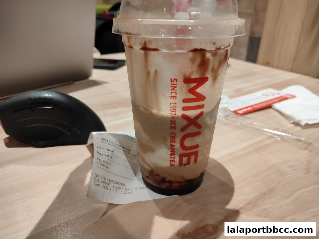 A cup of MIXUE Ice Cream Mocha with a receipt on a wooden table.