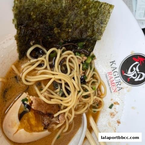 A close-up of a delicious bowl of Kagura Tokyo Chicken Ramen with a soft-boiled egg and nori.