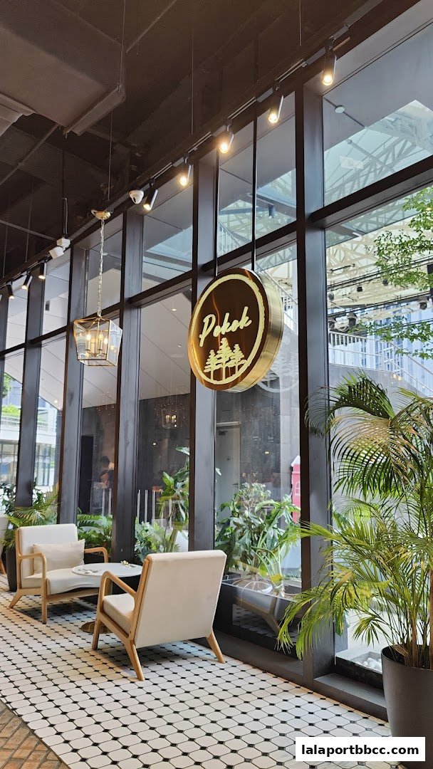 Interior seating area with chairs, a table, plants, and a hanging sign for POKOK.