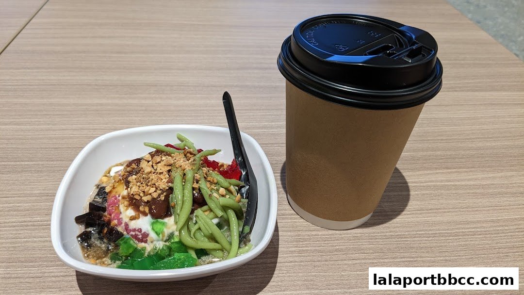A bowl of Cendol dessert with a cup of coffee on a wooden table.