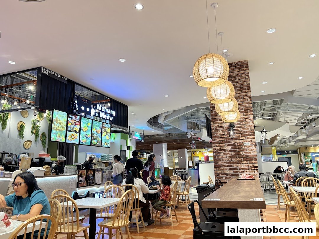 Interior view of Memang Meow cafe with customers dining and staff serving.