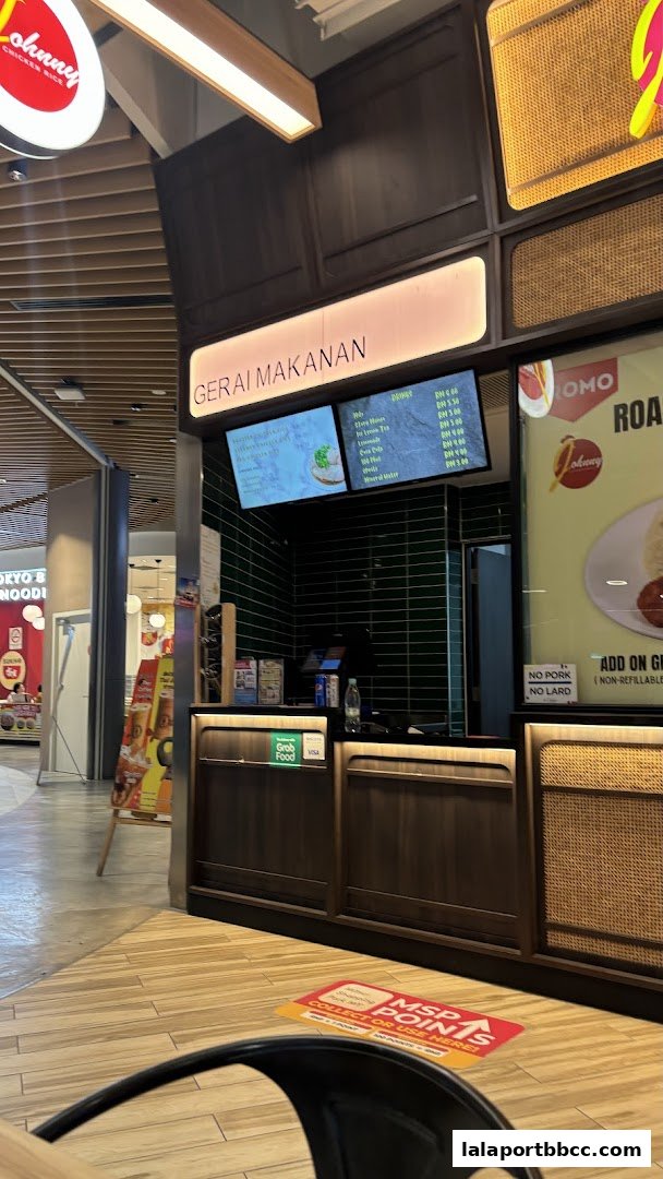 Johnny Chicken Rice LaLaport shop counter with menu screens and seating area.