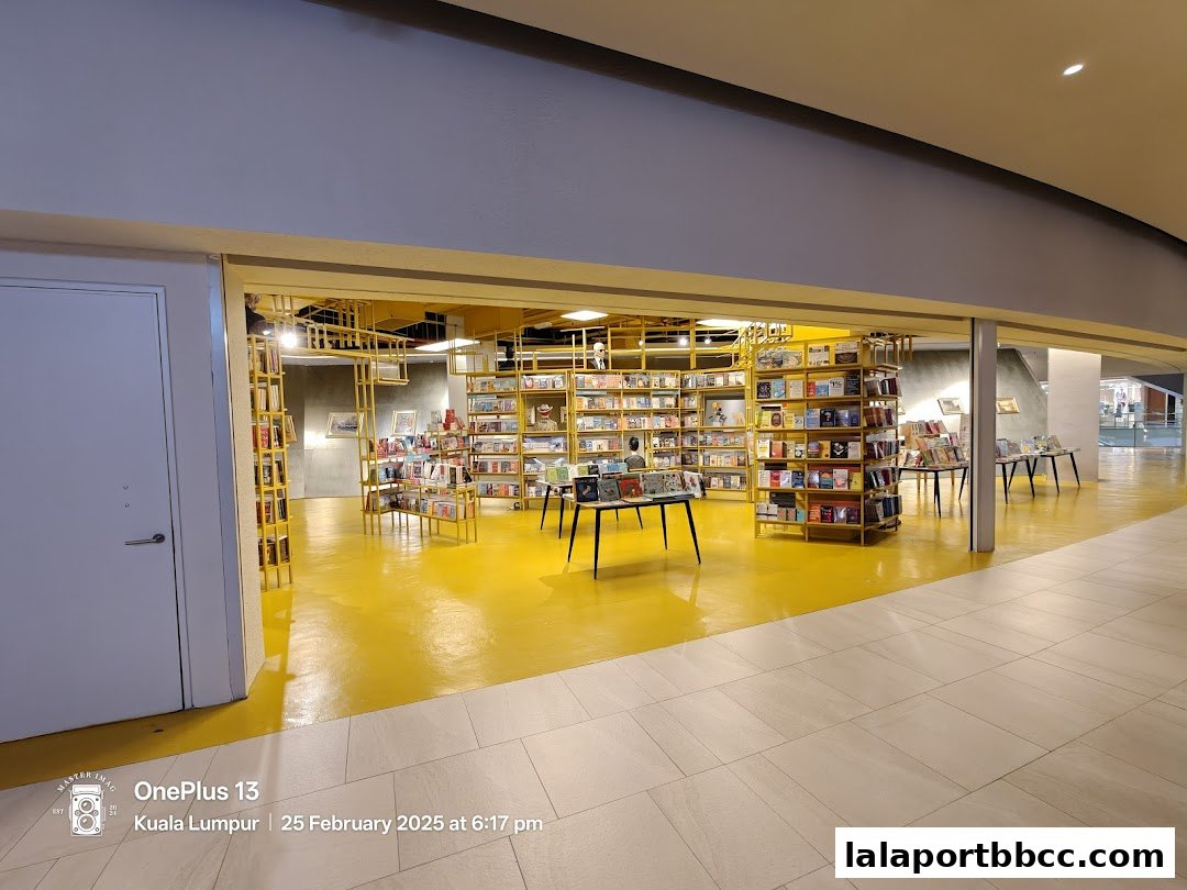 Interior view of a brightly lit bookstore with yellow floors and shelves filled with books.