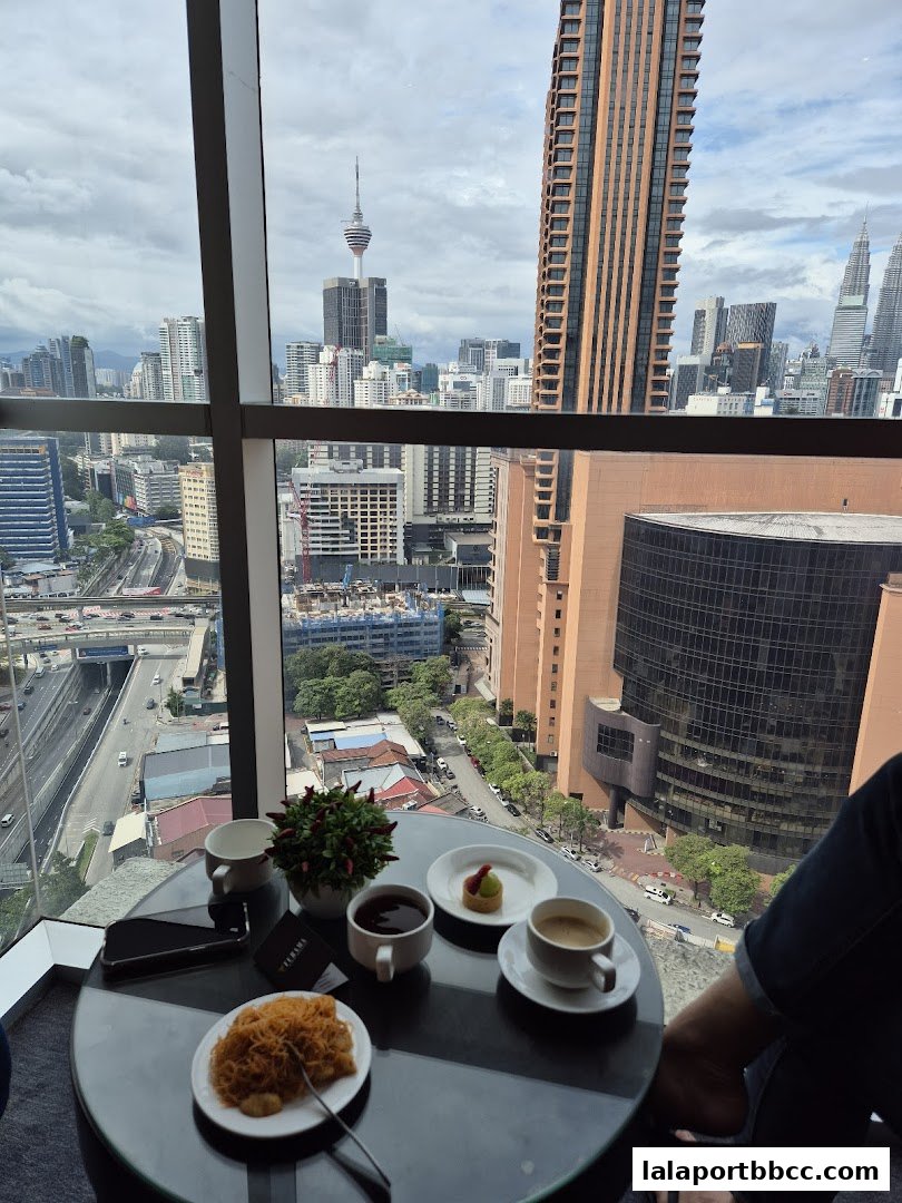 A table with coffee, tea, dessert, and snacks with a city skyline view.
