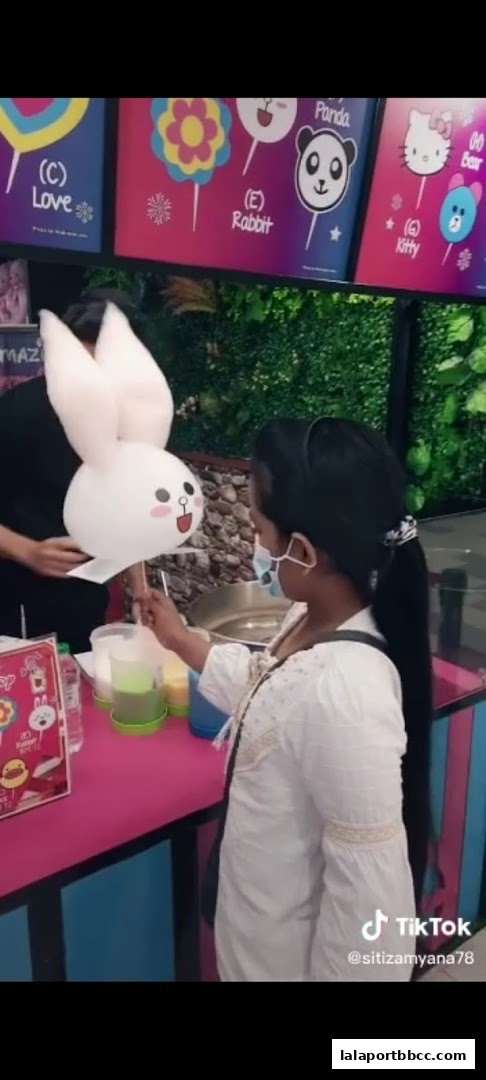 A customer receives a bunny-shaped cotton candy from a vendor at Amazing Cotton Candy.