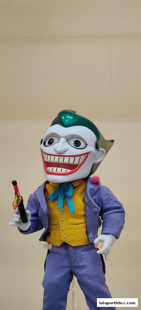 A detailed action figure of the Joker from Batman, holding a prop gun.