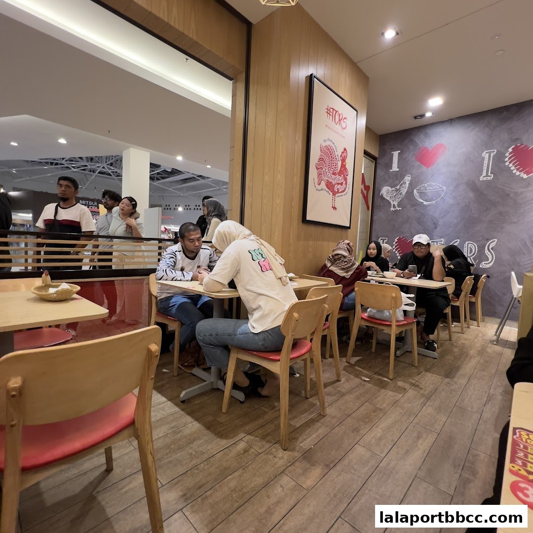 Diners seated at tables inside The Chicken Rice Shop, with decor on the wall.