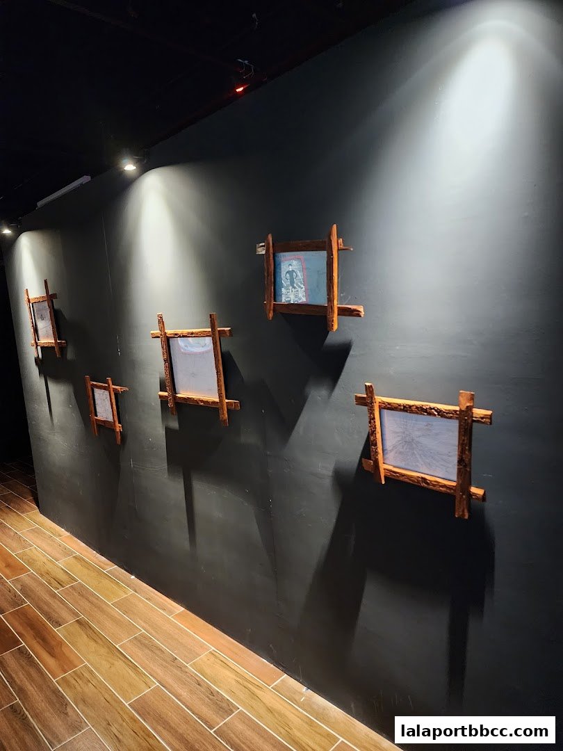 A dark wall with several framed artworks and dramatic lighting.