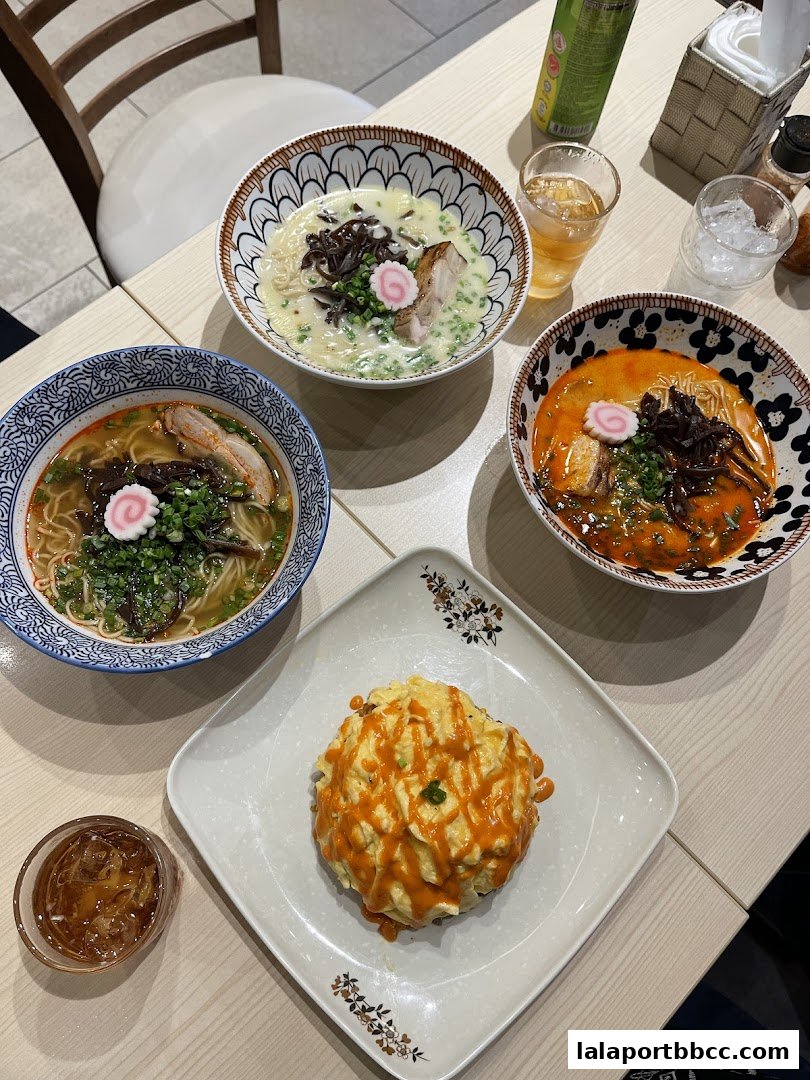 A table laden with three bowls of ramen and a dish of omurice, suggesting a delicious meal.