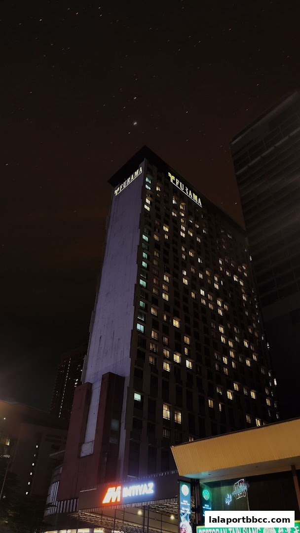 A tall hotel building with illuminated windows at night, featuring prominent signage.