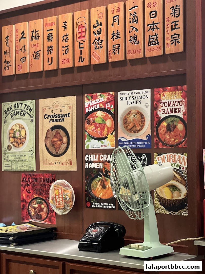 A wall display featuring various ramen dishes and Japanese drinks, with a vintage fan and telephone.