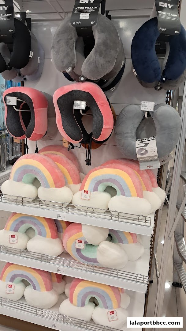 A display of colorful rainbow-shaped pillows and various neck pillows on shelves.