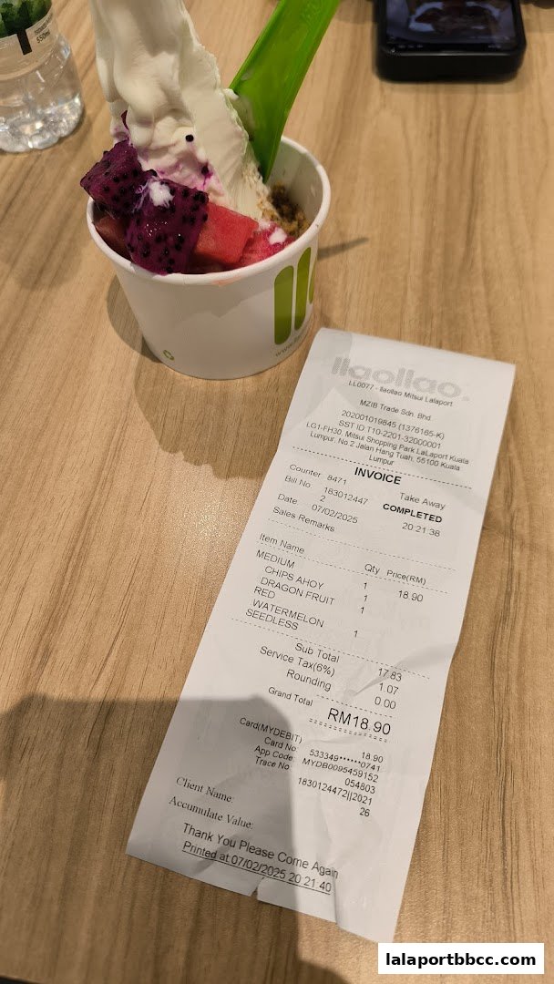 A cup of llaollao frozen yogurt with fruit toppings and a receipt.