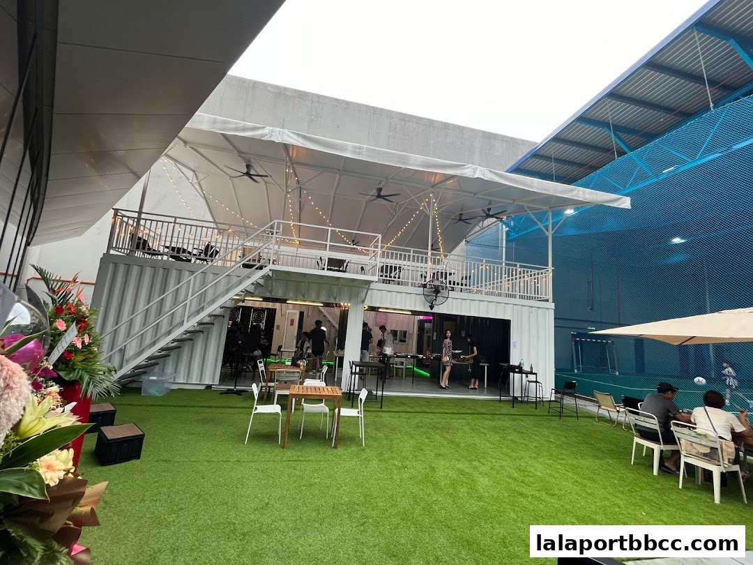 A multi-level outdoor seating area with tables and chairs, adjacent to a sports facility.