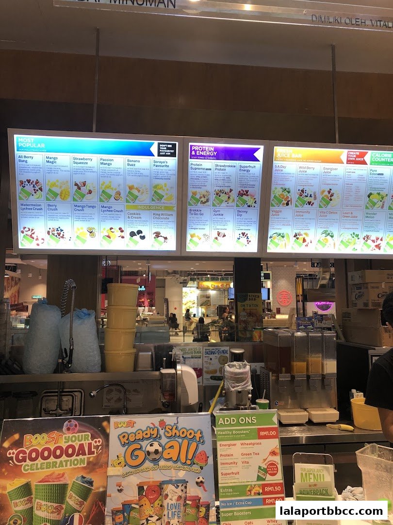 A brightly lit menu board displaying various juices, smoothies, and add-ons at Boost Juice.