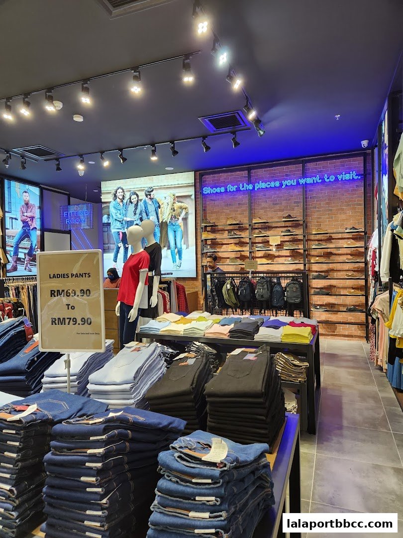 Interior view of a clothing store with stacks of jeans, mannequins, and shoes on display.