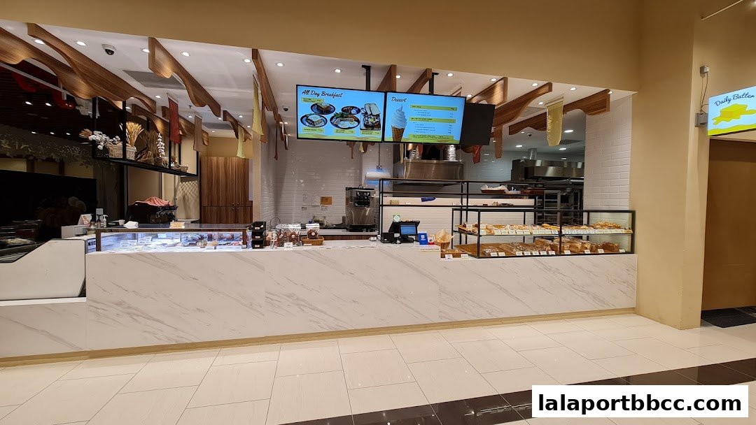 A clean and modern bakery counter with a display of pastries and digital menus.