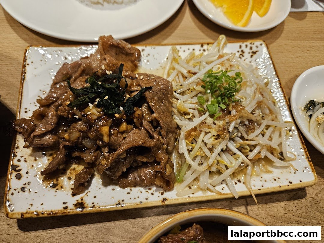 A plate of thinly sliced beef with bean sprouts and a side of rice.