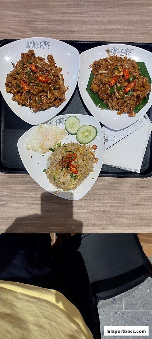 Three plates of Asian cuisine, including fried rice and noodles, are served on a tray.