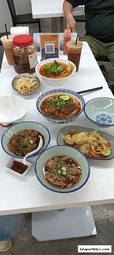 A table laden with various Hong Kong-style noodle dishes and drinks.