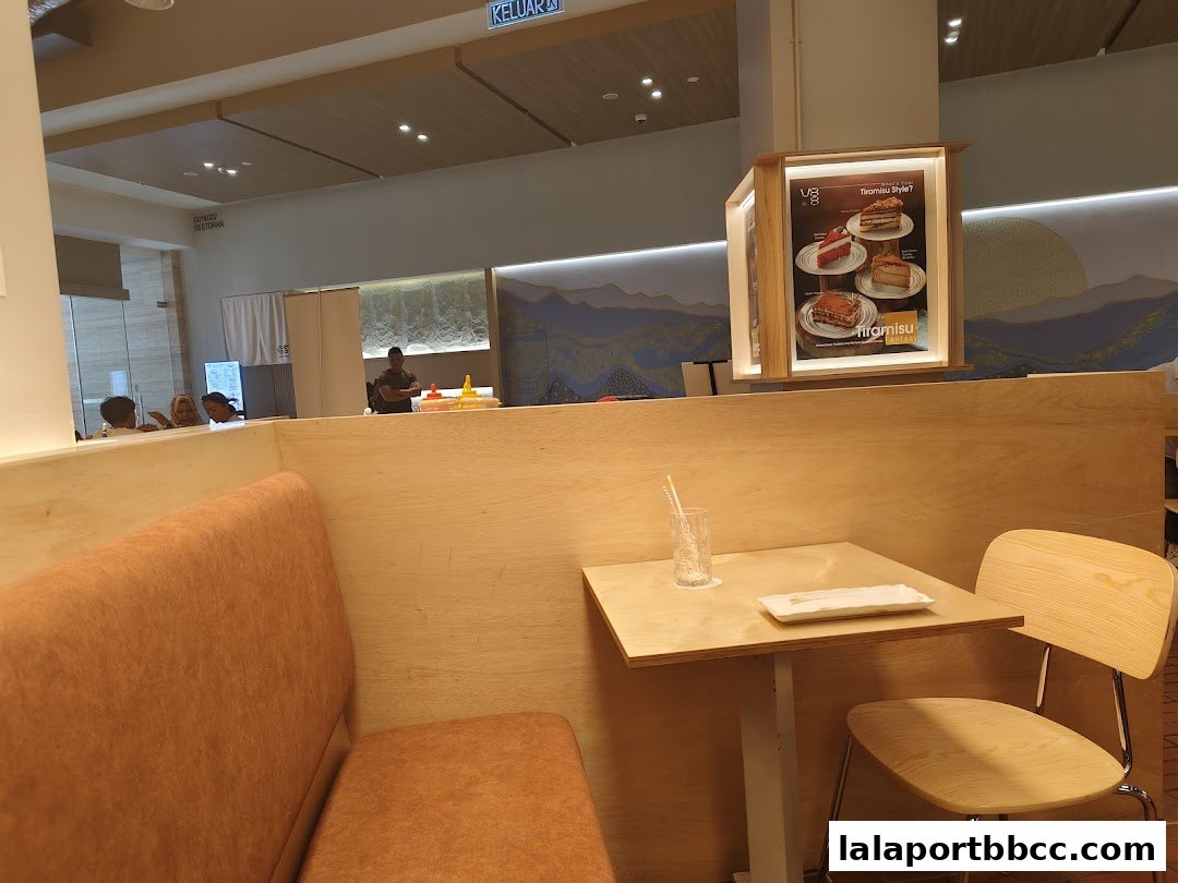 Interior shot of a cafe with a table, chair, and a display of desserts.
